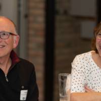 Two alumni smile at a table while speaking with other guests